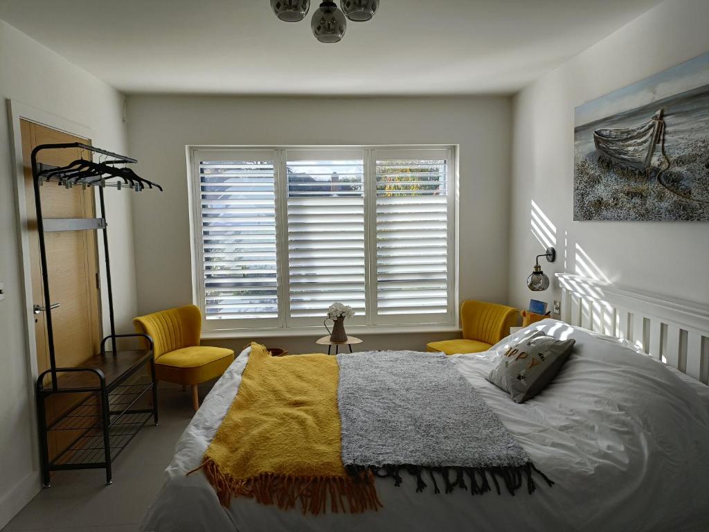 a bedroom with a bed and chairs and a window at Petite Anchorage in Christchurch