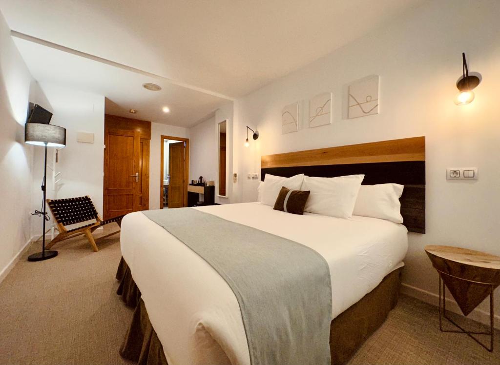 a hotel room with a large bed and a chair at LUZ Vejer Hospedería in Vejer de la Frontera