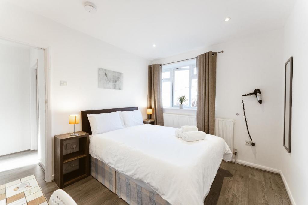 a white bedroom with a large bed and a window at Stepney Green beds to stay 24 in London