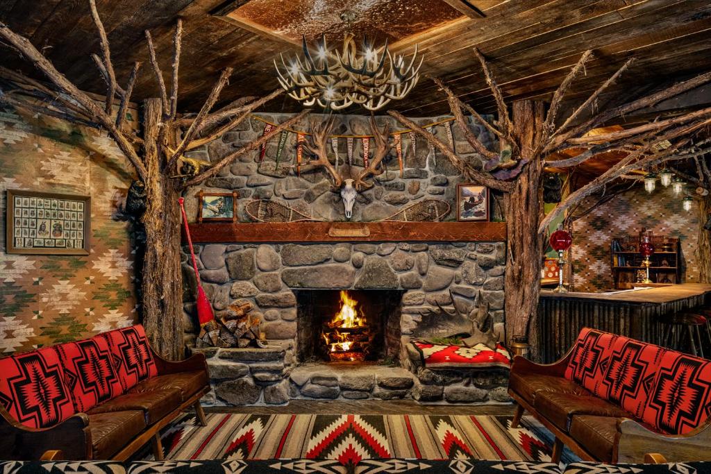 a living room with a stone fireplace and two couches at Urban Cowboy Lodge in Big Indian