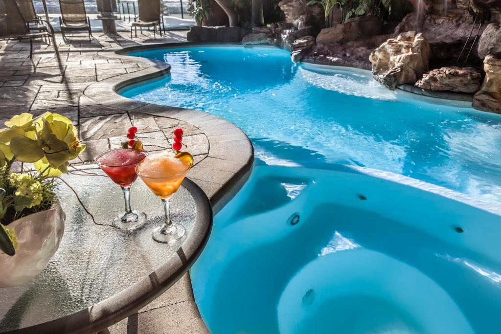 a pool with two cocktails on a table next to a swimming pool at Hotel Universel in Quebec City