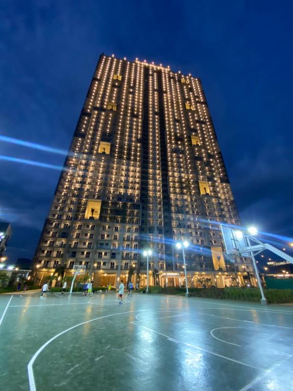 a tall building with a basketball court in front of it at 1BR Condo Unit at Celandine Condominium Near Ayala Cloverleaf Mall in Manila