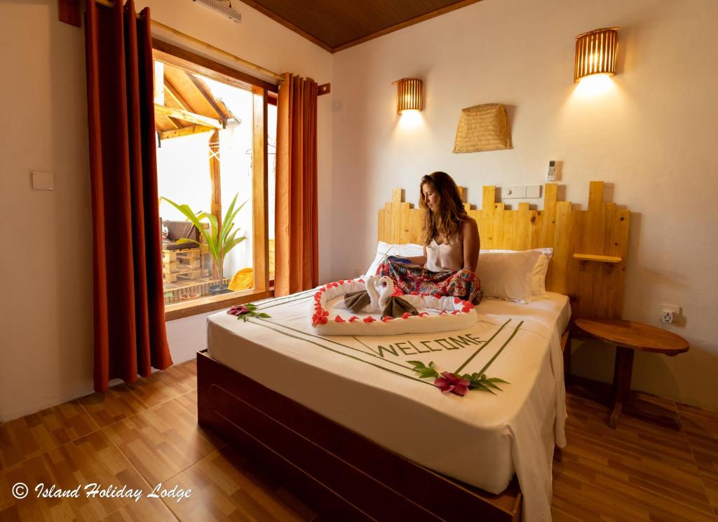 a woman sitting on a bed in a room at Island Holiday Lodge in Keyodhoo