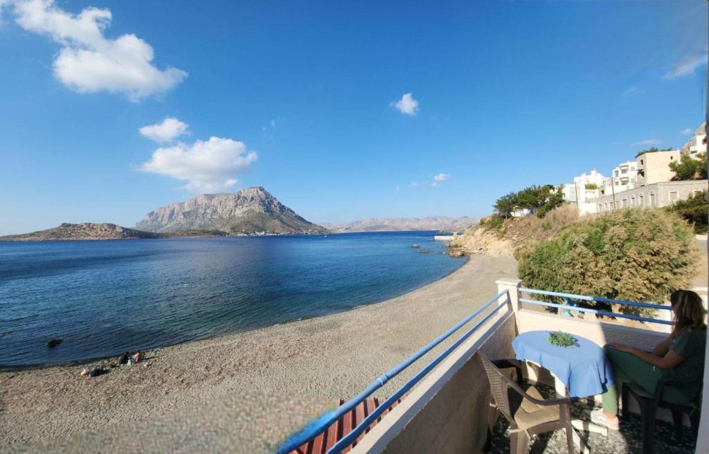 una mujer sentada en un balcón con vistas a la playa en Anna Studios, en Myrties