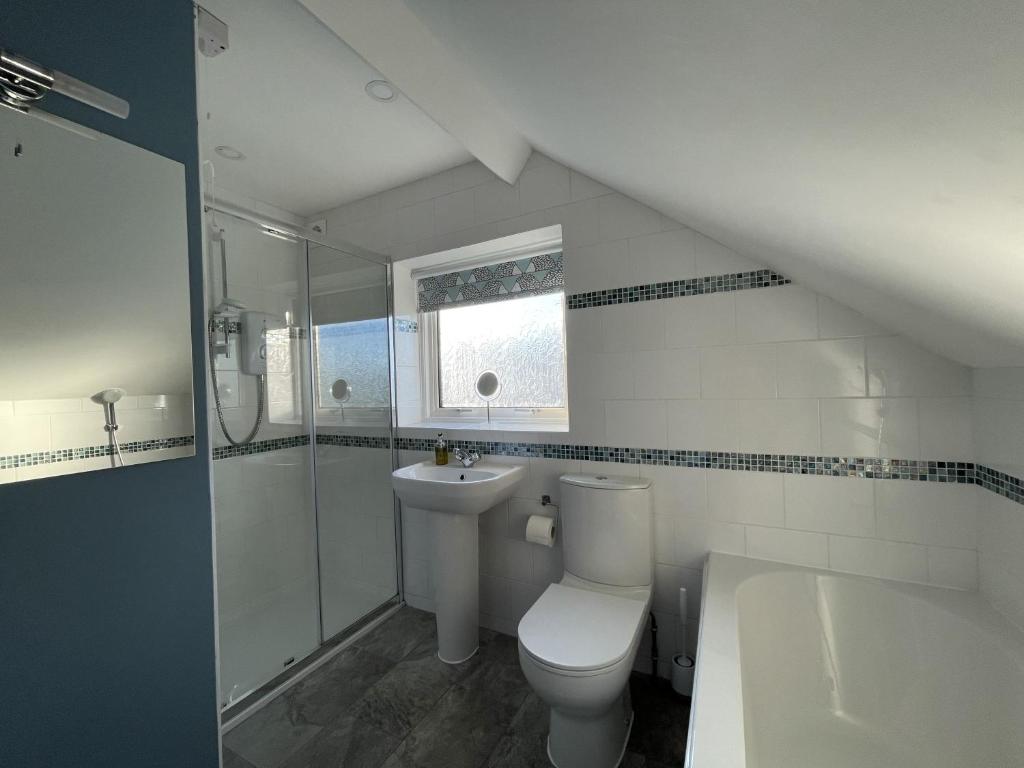 a white bathroom with a toilet and a sink at Roslin in Portinscale