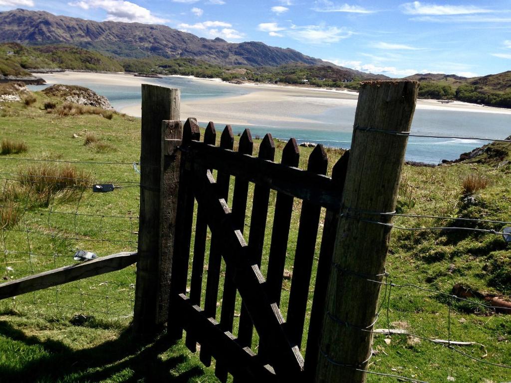 a wooden fence with a view of a beach at Bourblach in Mallaig