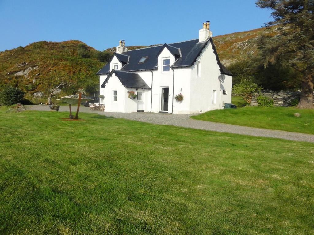 a white house with a green lawn in front of it at Bourblach in Mallaig