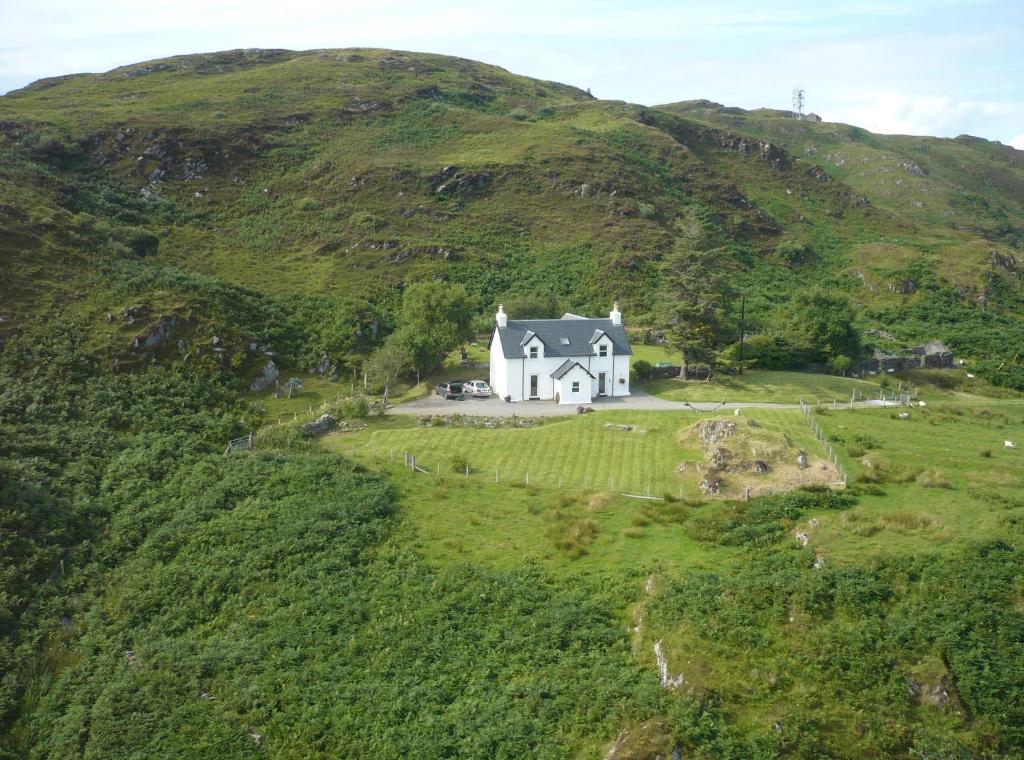 a large white house on a green hill at Bourblach in Mallaig