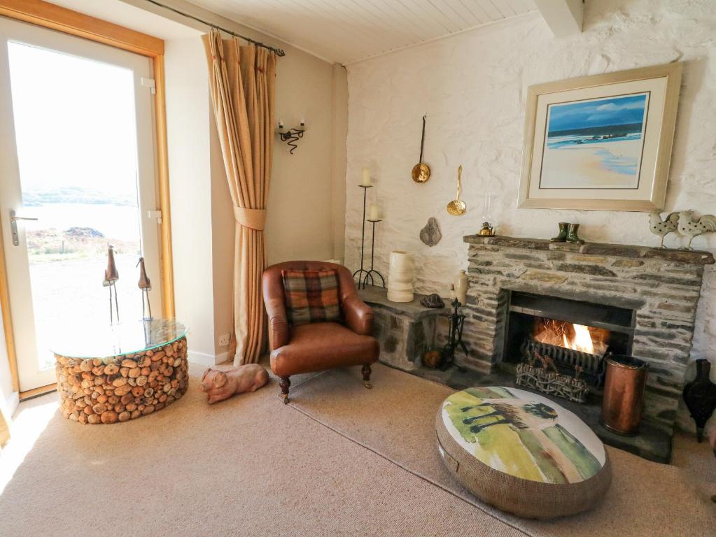 a living room with a fireplace and a chair at Bourblach in Mallaig