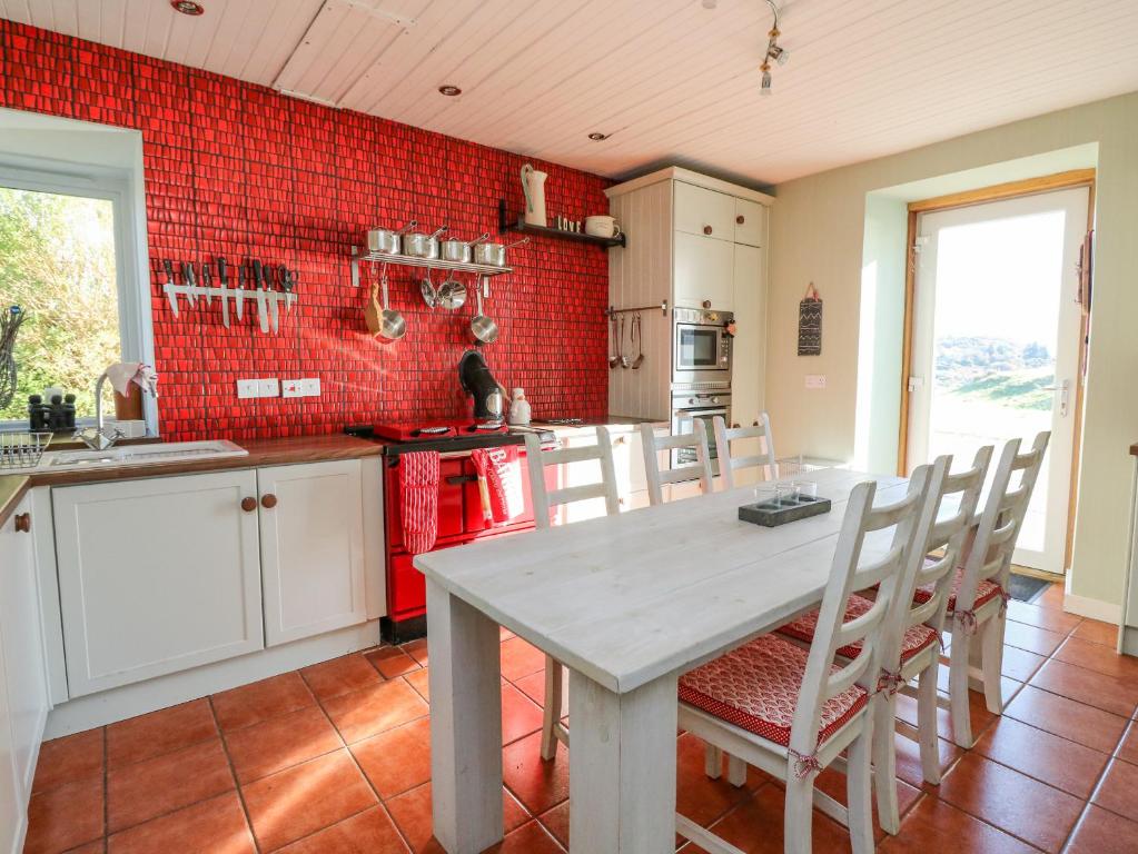a kitchen with a table and chairs and a red wall at Bourblach in Mallaig