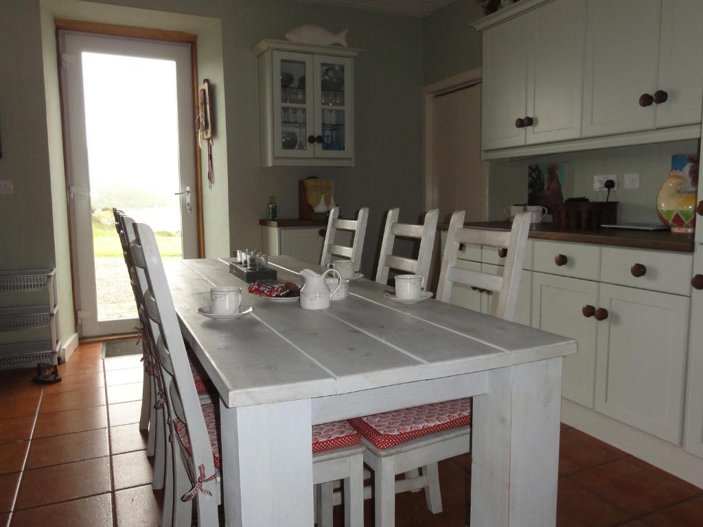 a kitchen with a white island with chairs and a table at Bourblach in Mallaig