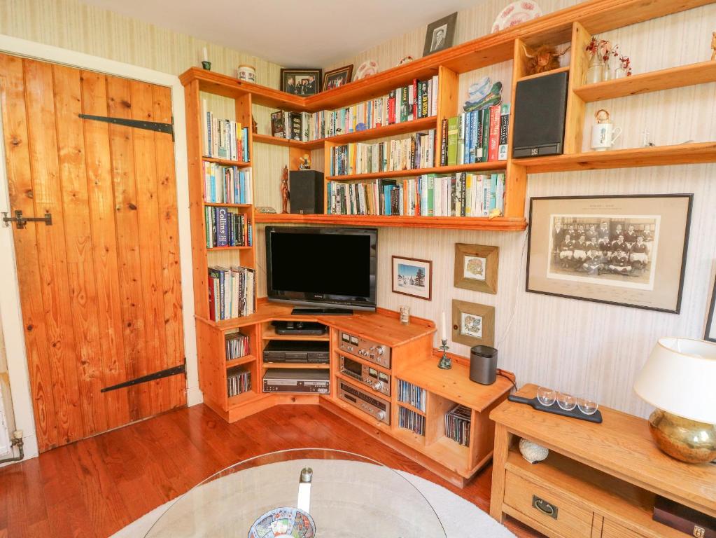 a living room with wooden bookshelves and a tv at Bourblach in Mallaig