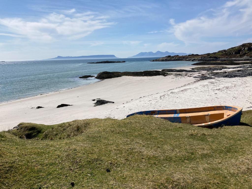 a boat sitting on a sandy beach next to the ocean at Bourblach in Mallaig