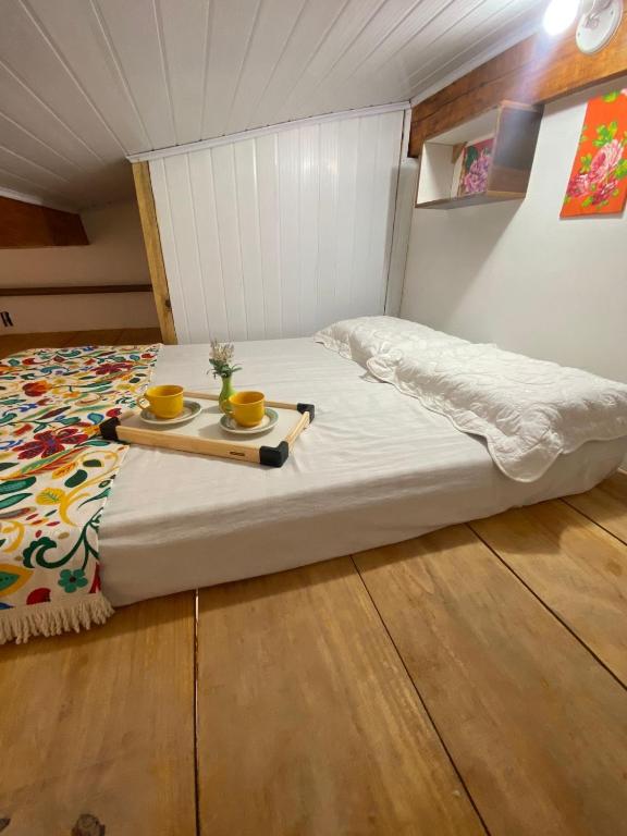 a bed with two cups and a tray on it at Casas Vasconcelos in Itacaré
