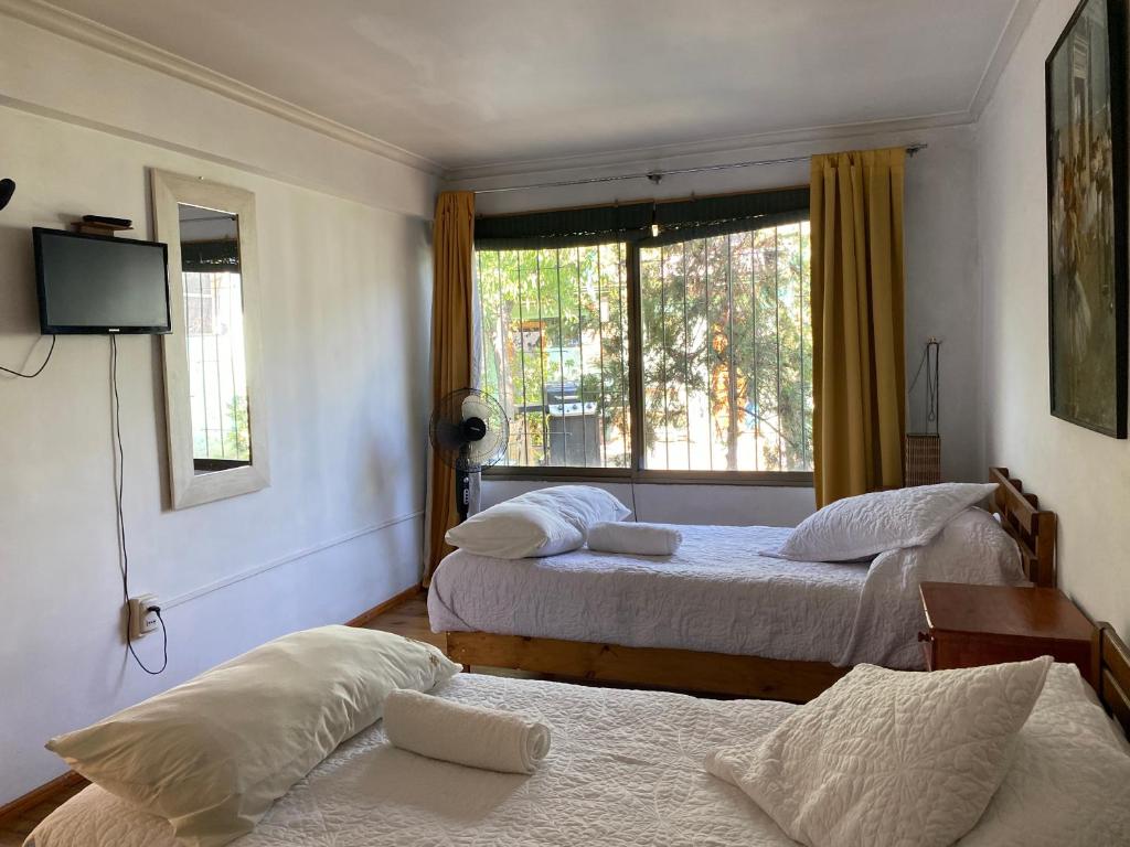 1 dormitorio con 2 camas y ventana en El Pillan "Travelers" House, en Santiago