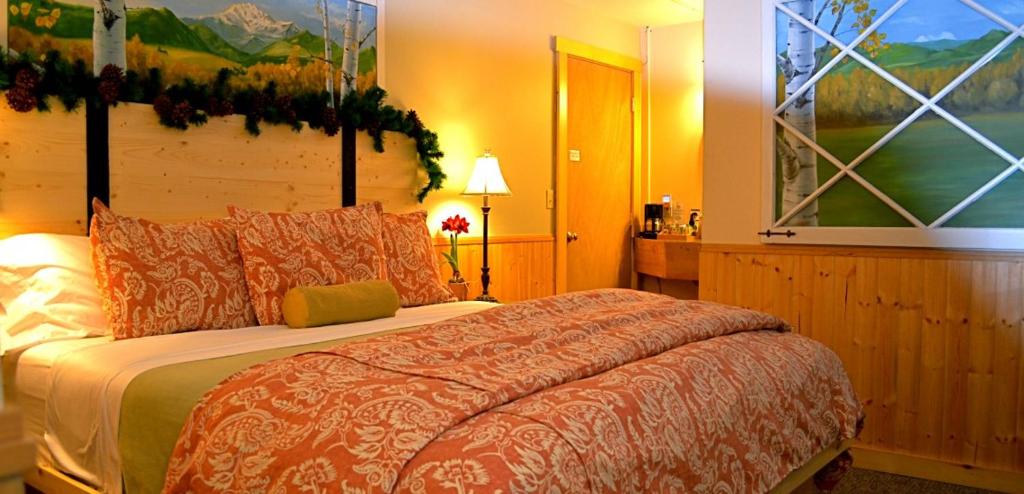 1 dormitorio con 1 cama y una pintura en la pared en Chewuch Inn & Cabins en Winthrop