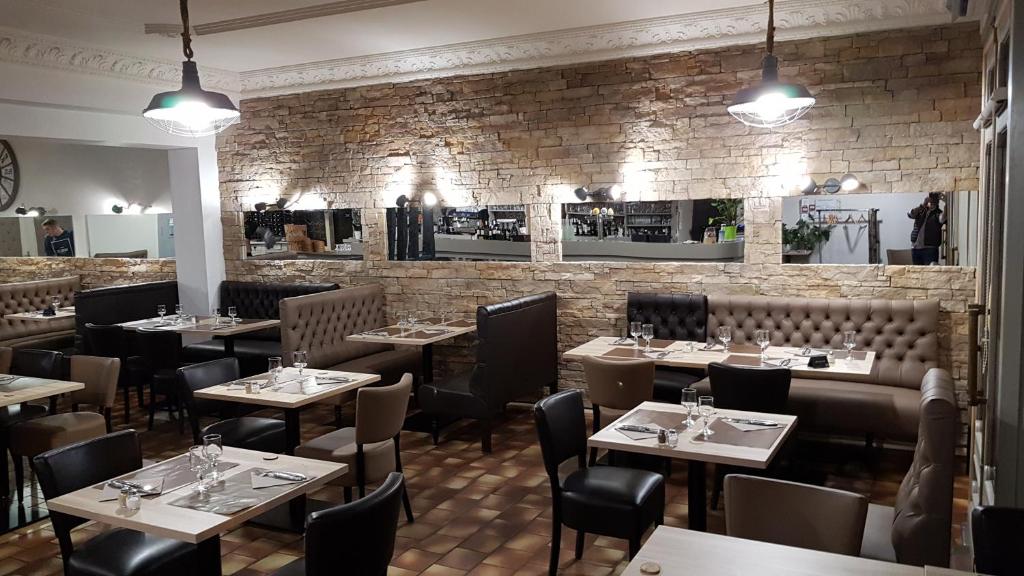 a restaurant with tables and chairs and a brick wall at Hôtel Restaurant Le Victor Hugo in Sainte-Foy-la-Grande