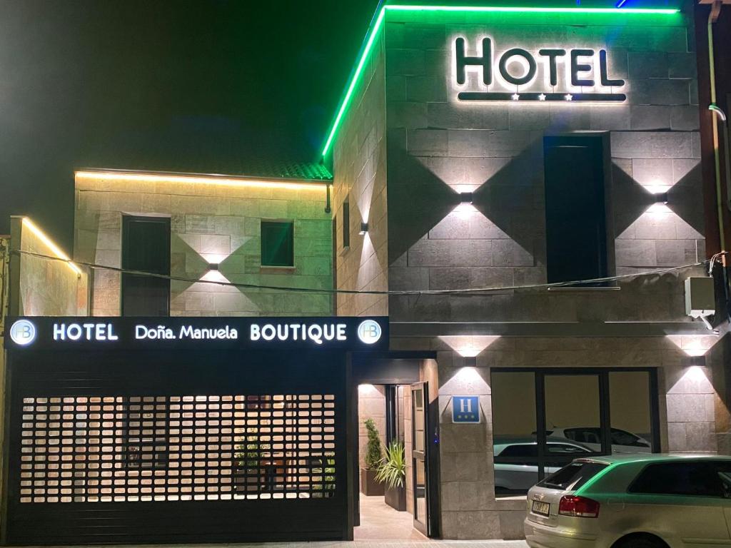 un hotel con un coche aparcado delante de él por la noche en HOTEL BOUTIQUE DOÑA MANUELA, en Tomelloso