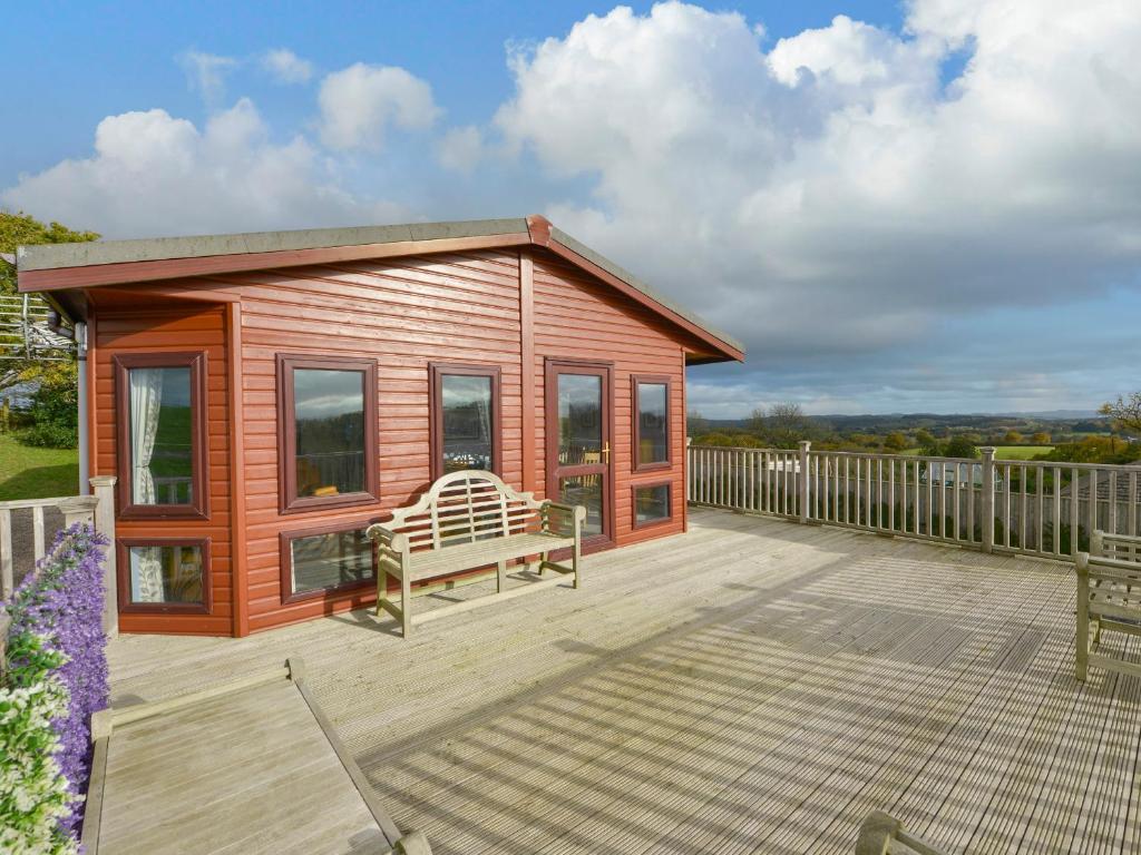 a small wooden cabin with a bench on a deck at Dartmoor View in Exeter