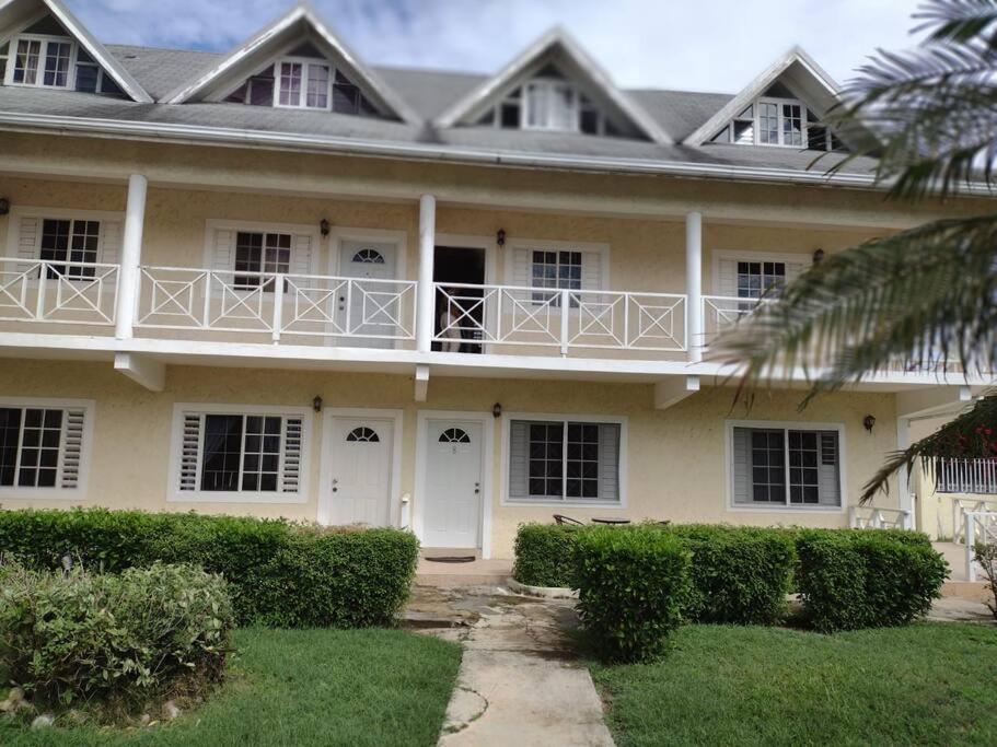 a white house with a balcony on top of it at Club Caribbean Apartments in Runaway Bay