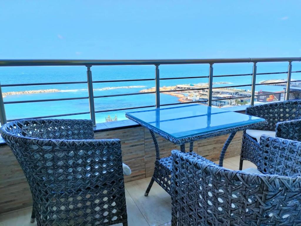 een tafel en stoelen op een balkon met uitzicht op de oceaan bij City Square - Brand New Luxury Apartment With Stunning Sea View in Alexandrië