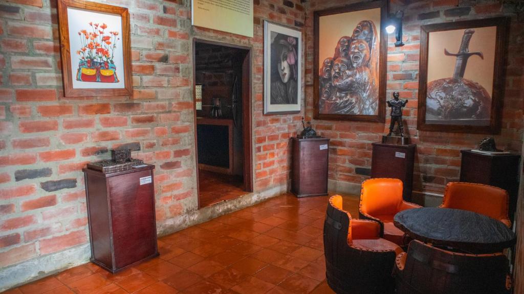 Habitación con pared de ladrillo, mesa y sillas. en Casa de Arte Monte Sinaí en Medellín