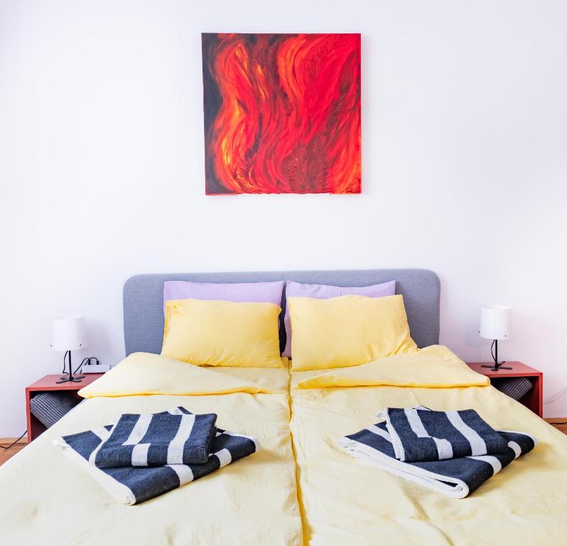 Pal's Favoriten Apartment في فيينا: سرير مع وسادتين ولوحة على الحائط