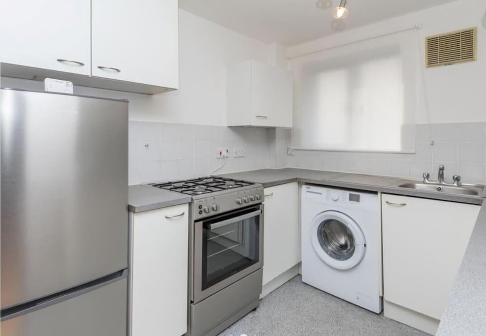 a white kitchen with a stove and a dishwasher at Bright, Spacious, Nice Interior, Close to the City, 2 Bedroom Apartment in London