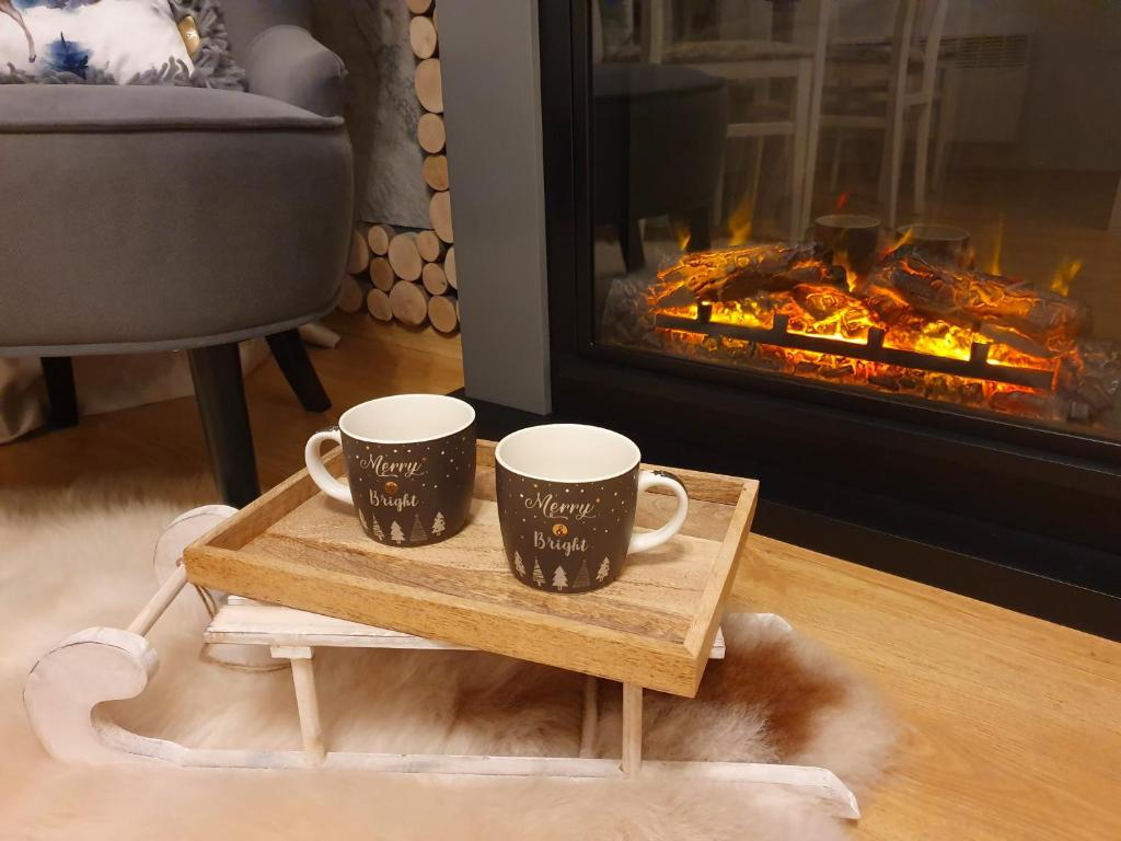 zwei Kaffeetassen auf einem Tisch vor einem Kamin in der Unterkunft Pinewood ANG Apartment, Semiramida Borovets Hills in Borowez