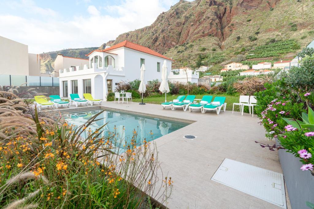 a house with a swimming pool with chairs and a mountain at Casa Paul do Mar in Paul do Mar