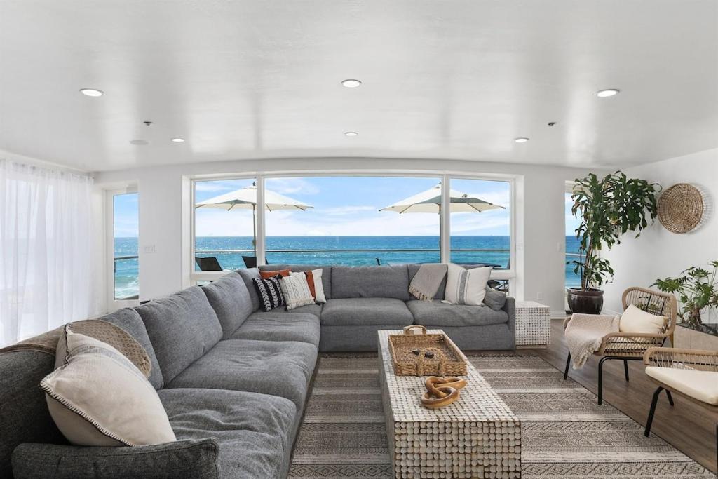 a living room with a gray couch and a view of the ocean at Oceanfront, Private Patio, BBQ, On The Strand in Oceanside