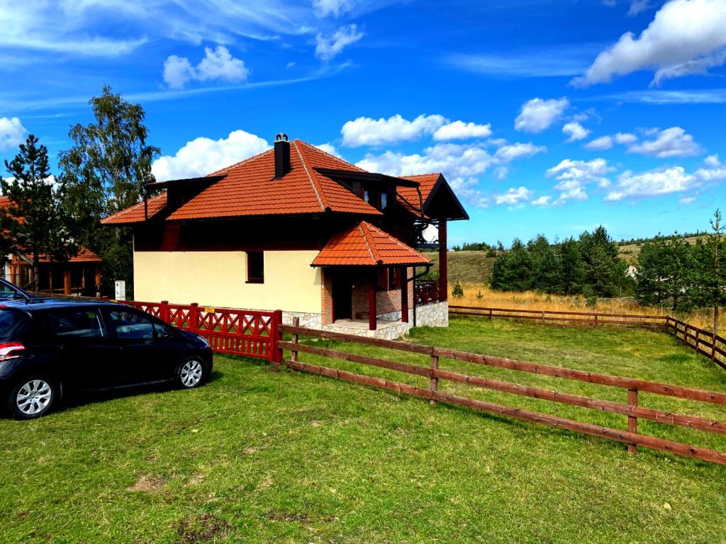 una casa con un coche aparcado junto a una valla en Ski House Tornik Zlatibor en Zlatibor