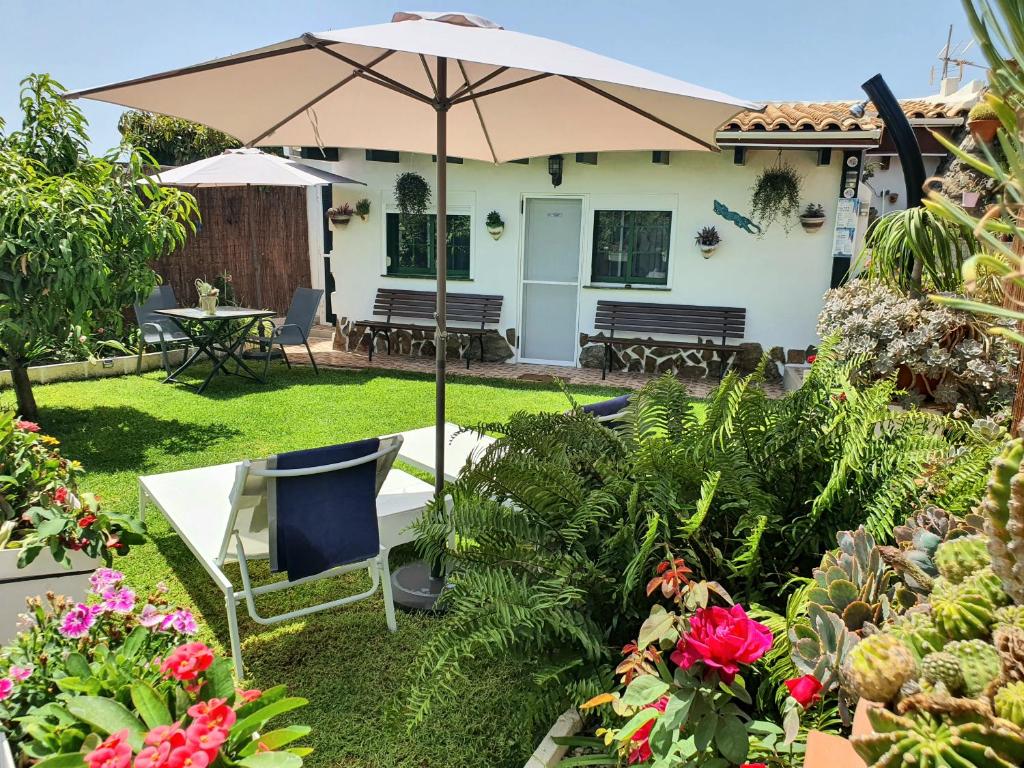 um pátio com um guarda-sol, cadeiras e flores em Casa Rural Eneida em Chiquenge