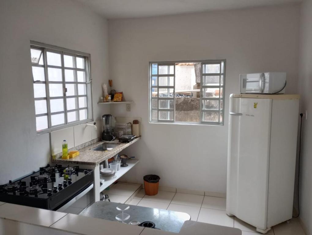 a kitchen with a white refrigerator and a sink at Casa da Pirâmide in São Thomé das Letras