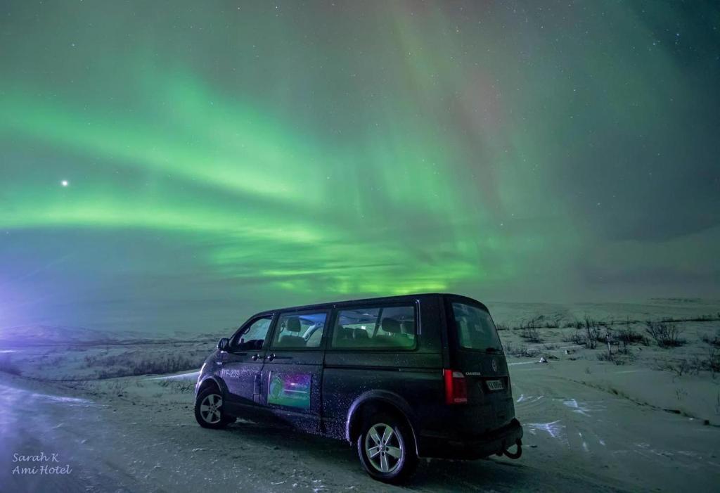 a car parked on a snow covered road under the aurora at Ami Hotel in Tromsø