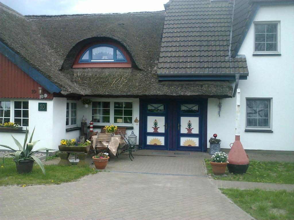 a white house with a blue door and some plants at Pension Martens - Gaubenwohnung in Wieck
