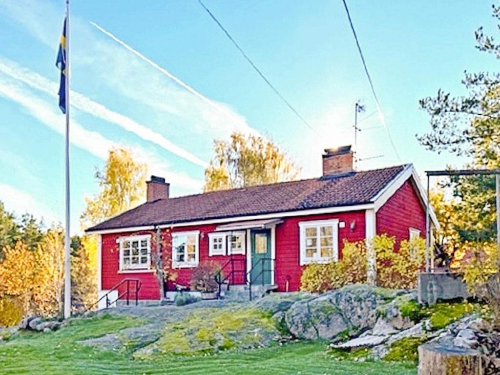 een rood huis met een vlag ervoor bij Holiday home HANINGE II in Haninge