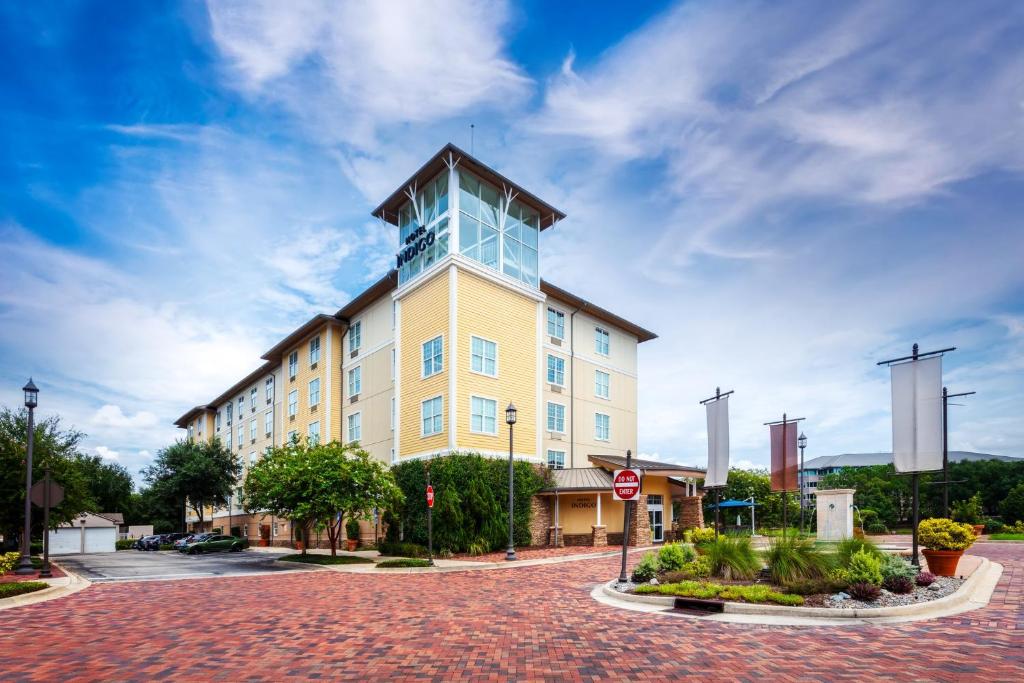 a large yellow building with a clock tower on a street at Hotel Indigo Jacksonville-Deerwood Park, an IHG Hotel in Jacksonville