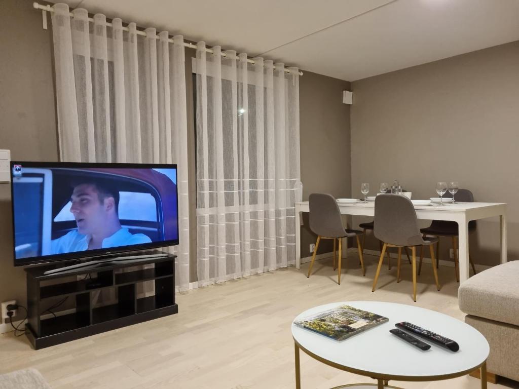 uma sala de estar com uma televisão de ecrã plano e uma mesa em Chausseen Apartment 