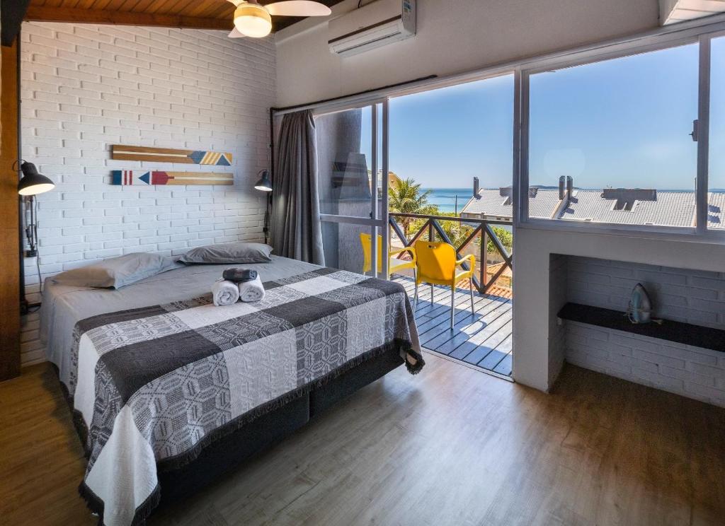 a bedroom with a bed and a view of the ocean at Loft Califórnia in Bombinhas