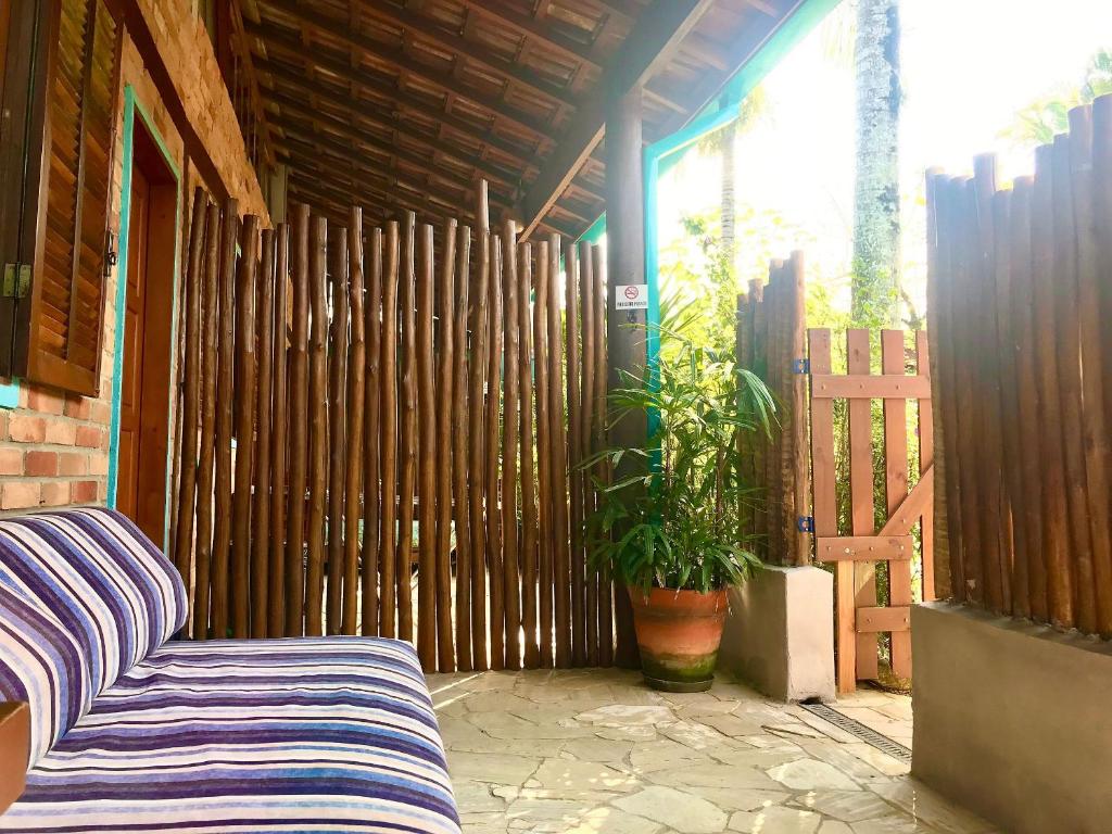 a porch with a couch and a wooden fence at Chalés Água Grande in Maresias