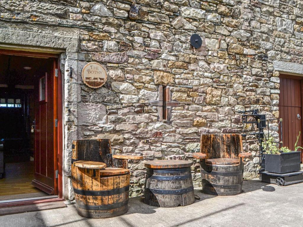 a stone building with three wooden barrels in front of a building at The Bothy in Dearham