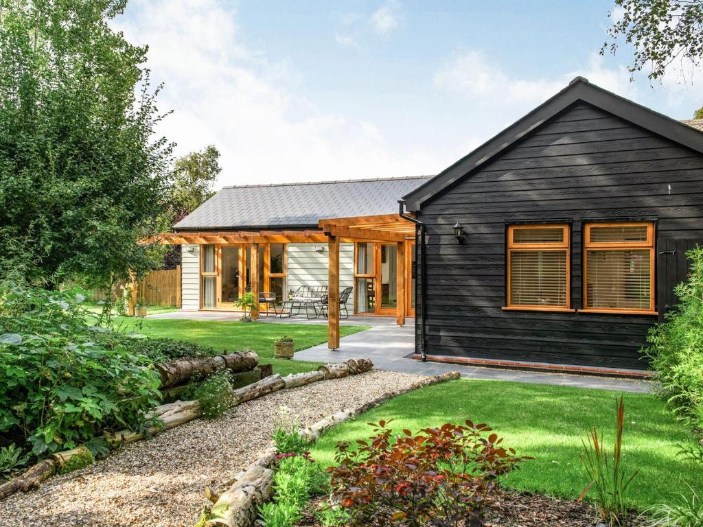 a black house with orange windows and a yard at North Farm Lodge in East Mersea