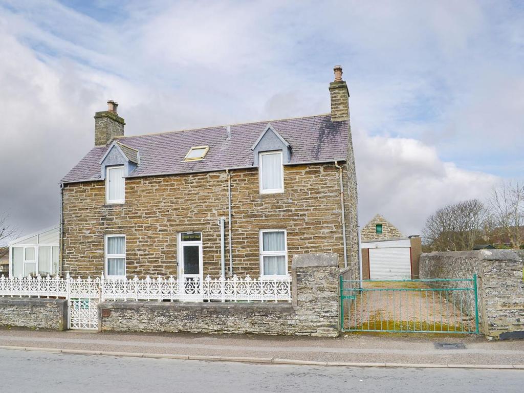 a brick house with a white fence in front of it at Moray Cottage in Wick