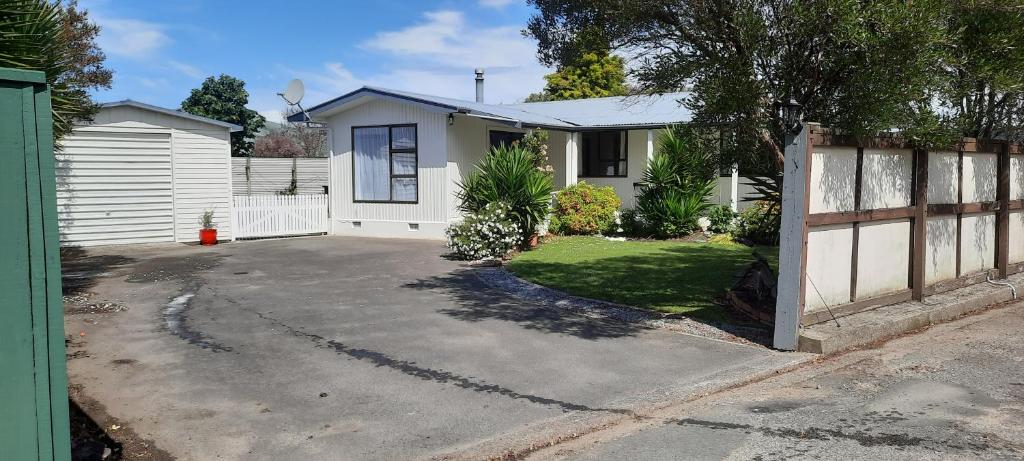 a white house with a fence and a driveway at Cosy on Courtney in Motueka