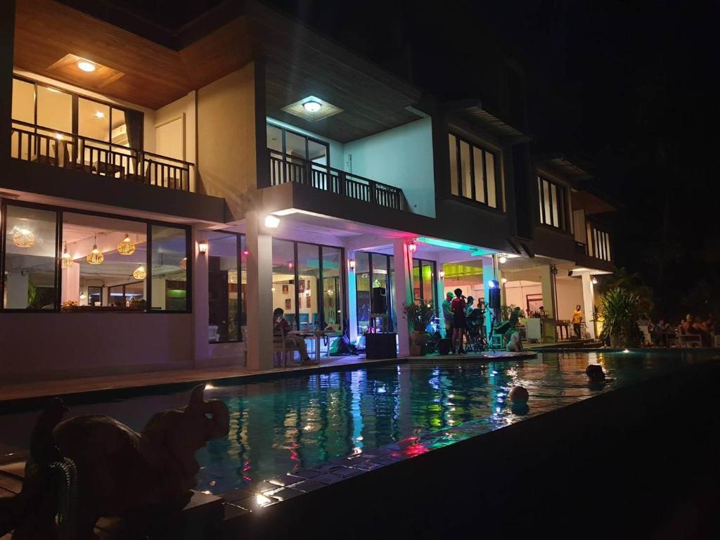 a swimming pool in front of a building at night at Baan Ampai Beach Hotel in Hua Thanon Beach