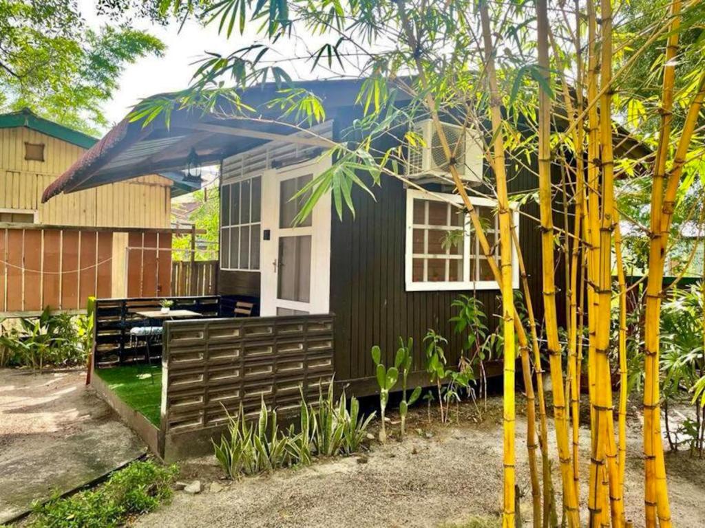 una pequeña casa negra con techo azul en Blissful Cottage, en Pantai Cenang