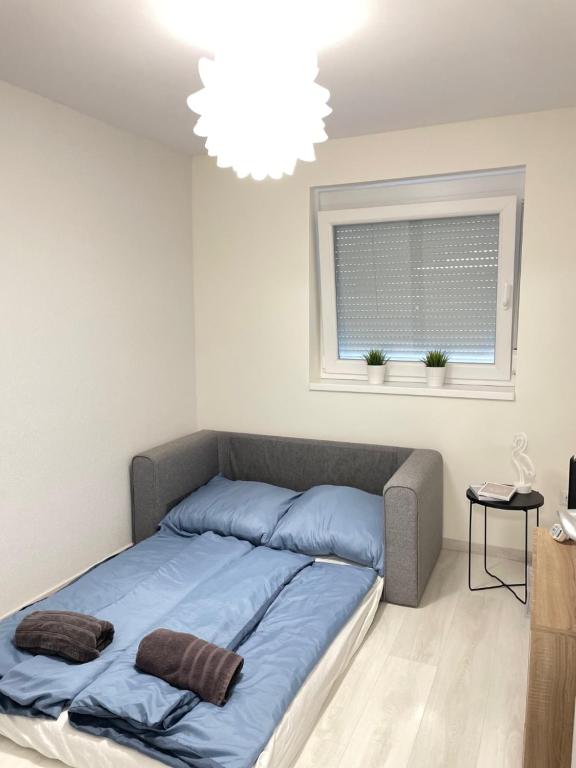 1 dormitorio con 1 cama con manta azul y ventana en Relax Nyaraló Dombori, en Fadd-Dombori
