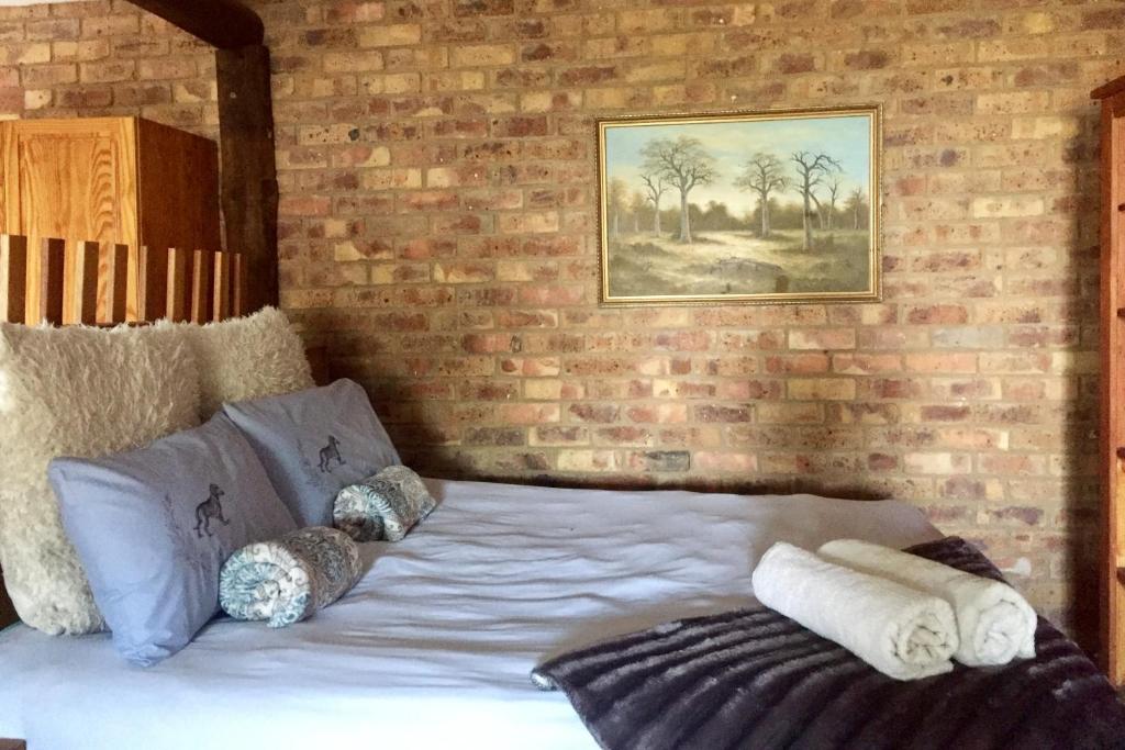 een bed in een kamer met een bakstenen muur bij Villa Dachie in Rayton