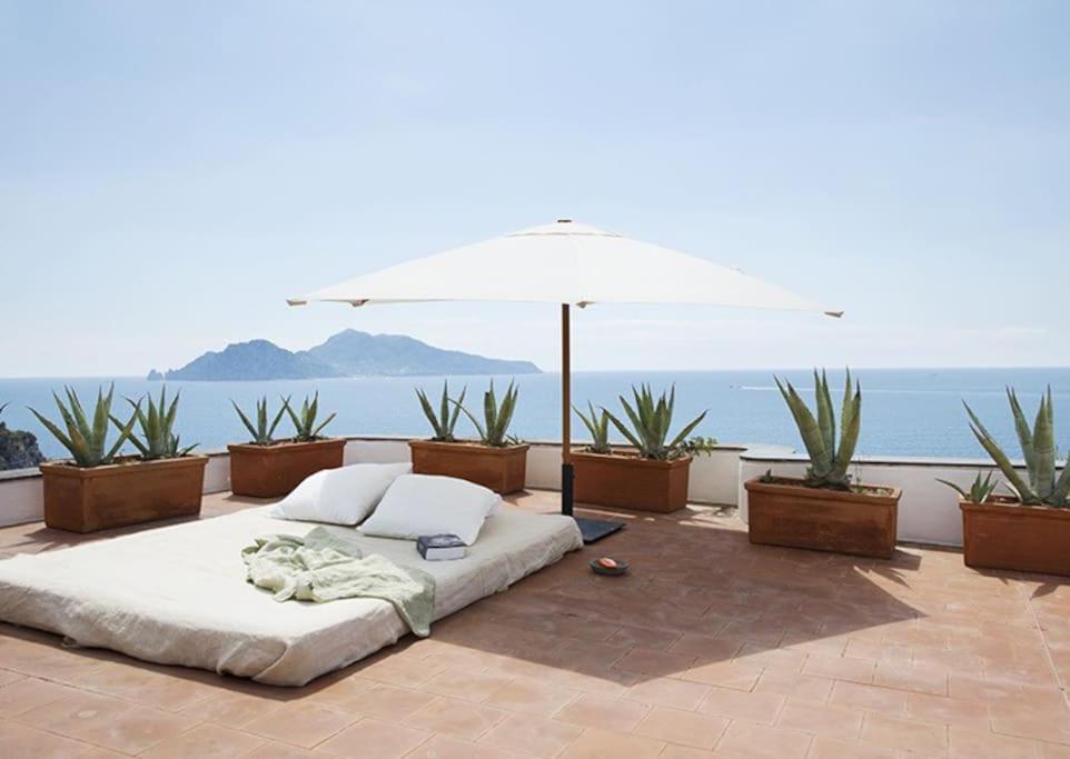 a bed sitting on a patio with an umbrella at Villa Bianca in Massa Lubrense